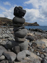 Stack of pebbles on beach against sky