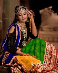 Young woman looking away wearing traditional clothing sitting outdoors