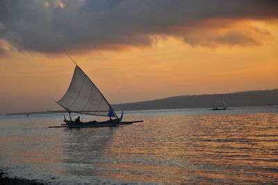 Silhouette sailboat on sea against sky during sunset