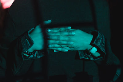 Midsection of woman with interlocked hands at night