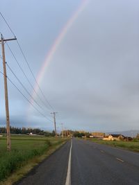 Scenic view of rainbow over road against sky