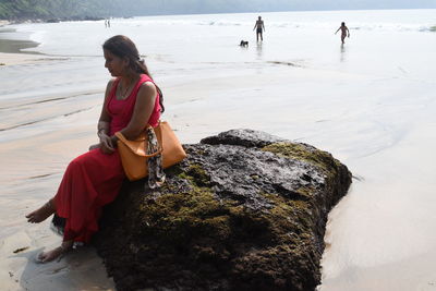 Woman sitting on rock at beach