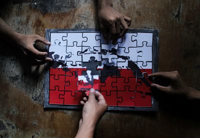 Cropped hands of people playing with jigsaw puzzle on table