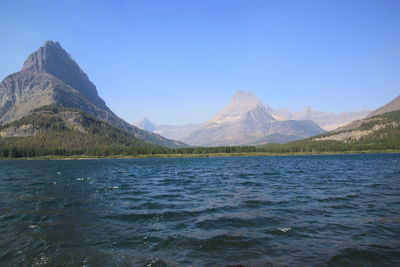 Scenic view of sea and mountains against clear blue sky