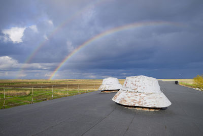 Rainbow over road against sky