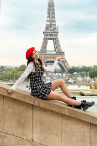 Portrait of young woman sitting on railing