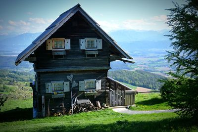 Built structure on field by houses against sky