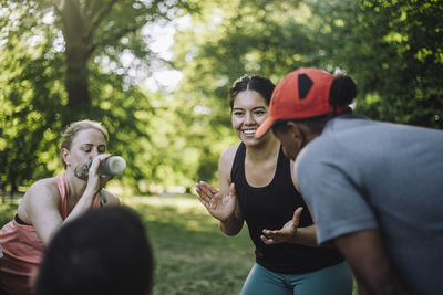 Smiling female coach motivating team during training at park