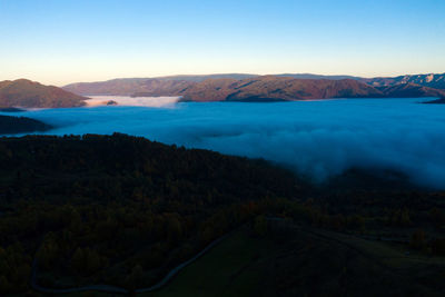 Aerial drone view of mist and clouds in the valley in sunrise. flying above the clouds