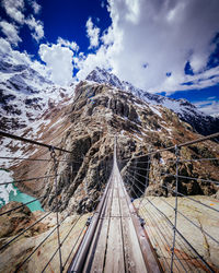 Snow covered footbridge against sky