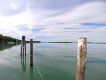 Wooden posts in water against sky