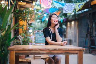 Portrait of a smiling young woman sitting on table