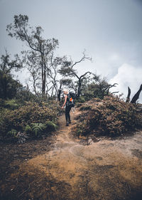 Full length of woman standing by plants against sky