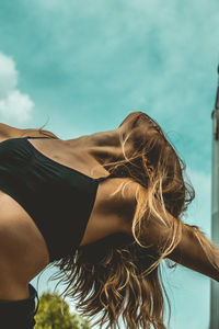 Low angle view of young woman against sky