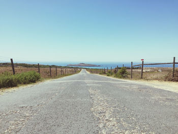 Empty road against clear blue sky