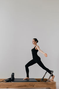 Side view of young man exercising on hardwood floor against clear sky