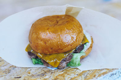 Close-up of hamburger on tissue paper at table