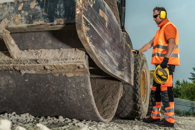 Worker standing by bulldozer at construction site