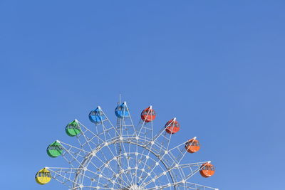 Low angle view of ferris wheel against clear blue sky