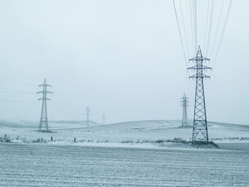 Electricity pylon on field against sky during winter