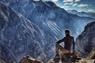 Man sitting on rock against mountains