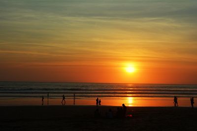 Silhouette people on beach against sky during sunset