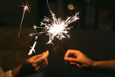 Midsection of woman holding sparkler at night