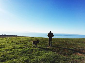 Rear view of man and dog against clear sky