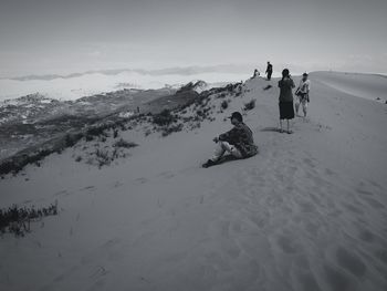 People on snowcapped mountain against sky