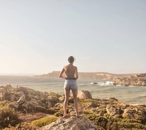 Rear view of woman looking at sea against clear sky