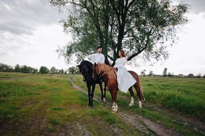 Couple riding horses on field