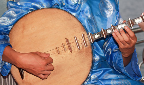 Midsection of person playing traditional guitar