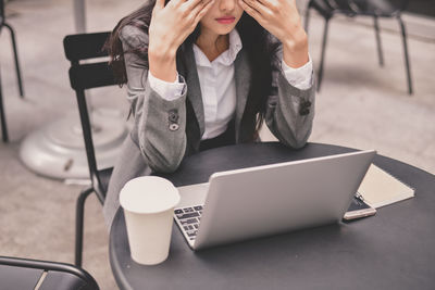 Midsection of tired businesswoman sitting at table in cafe