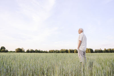 Farmer with hands in pockets standing on cornfield