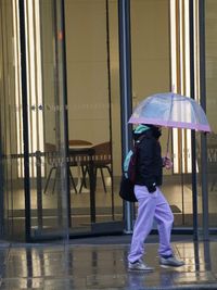 Rear view of man with umbrella walking in city