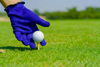 Hand golfer hold golf ball with tee ready to be shot at golf court.
