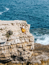 Young woman in summer clothes and hat on cliffs above sea. waves, nature, summer, travel.