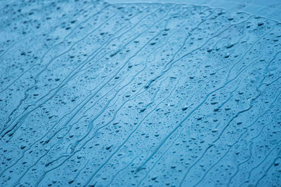 Full frame shot of raindrops on blue glass