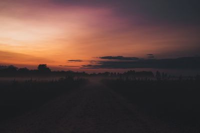 Scenic view of agricultural field against sky at sunset