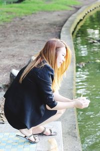 Woman crouching at lakeshore