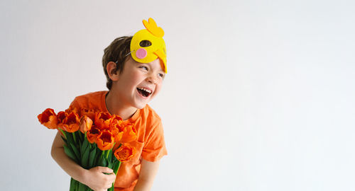 Cheerful boy holding bouquet against white background
