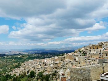 View of cityscape against cloudy sky