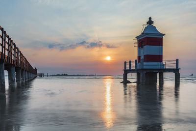 Pier over sea against sky during sunset