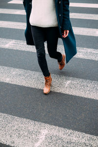 Low section of woman walking on road