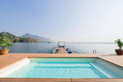 Swimming pool by sea against clear sky