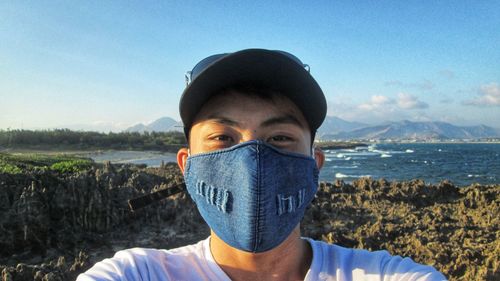 Portrait of young woman standing against sky