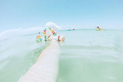 People swimming in sea against clear sky