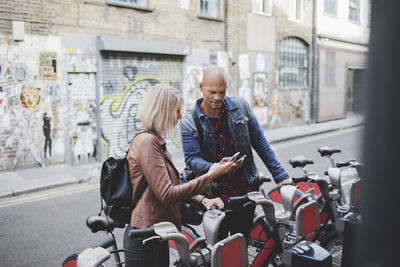 Couple using mobile phones at bicycle sharing system