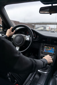 Midsection of man using smart phone in car