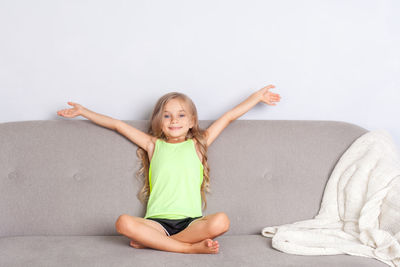 Portrait of smiling girl sitting against wall